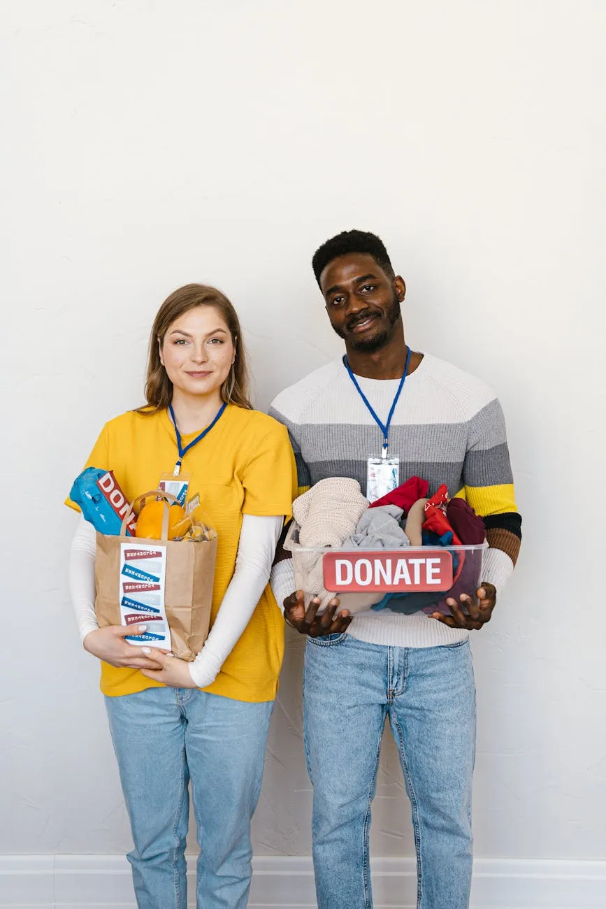 Two volunteers holding a donation box and a bag of supplies