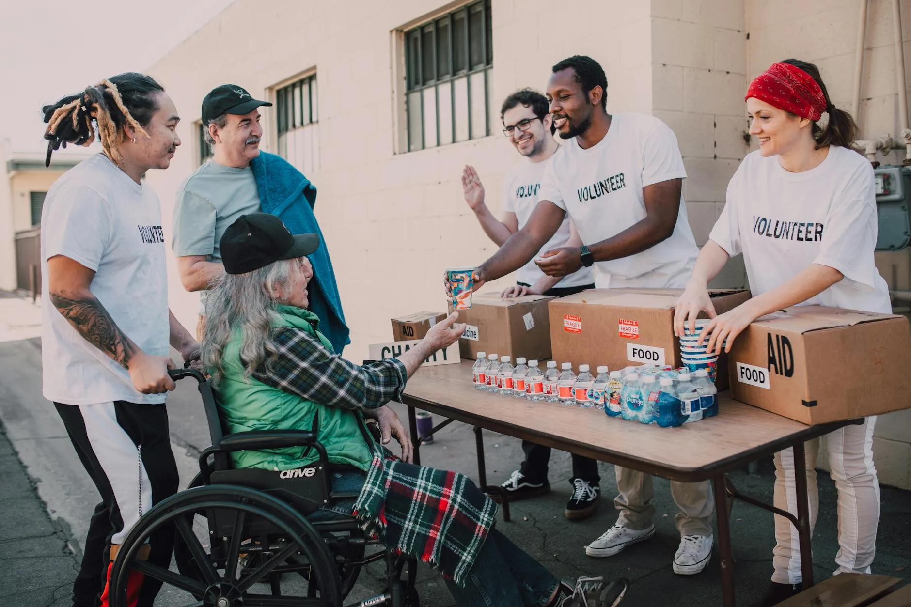 Volunteers handing out food and water to a woman in a wheelchair